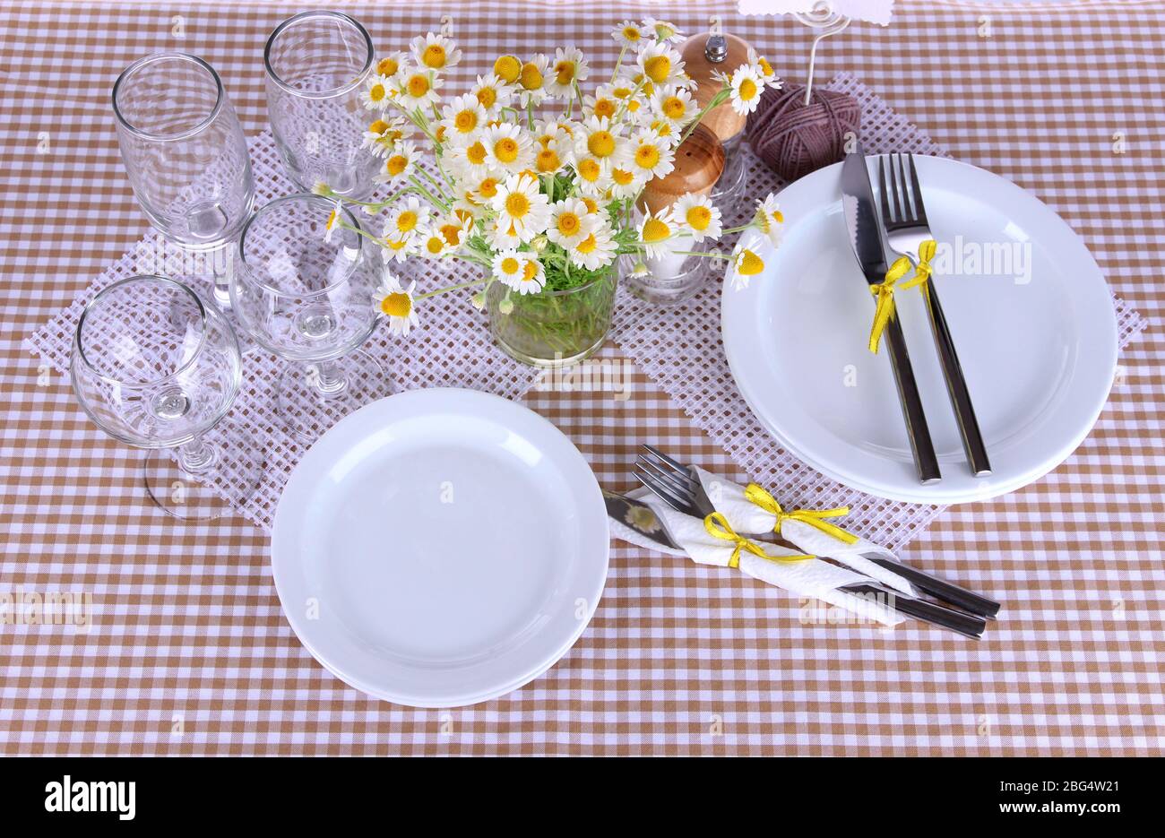 Table setting with chamomiles on checkered tablecloth Stock Photo