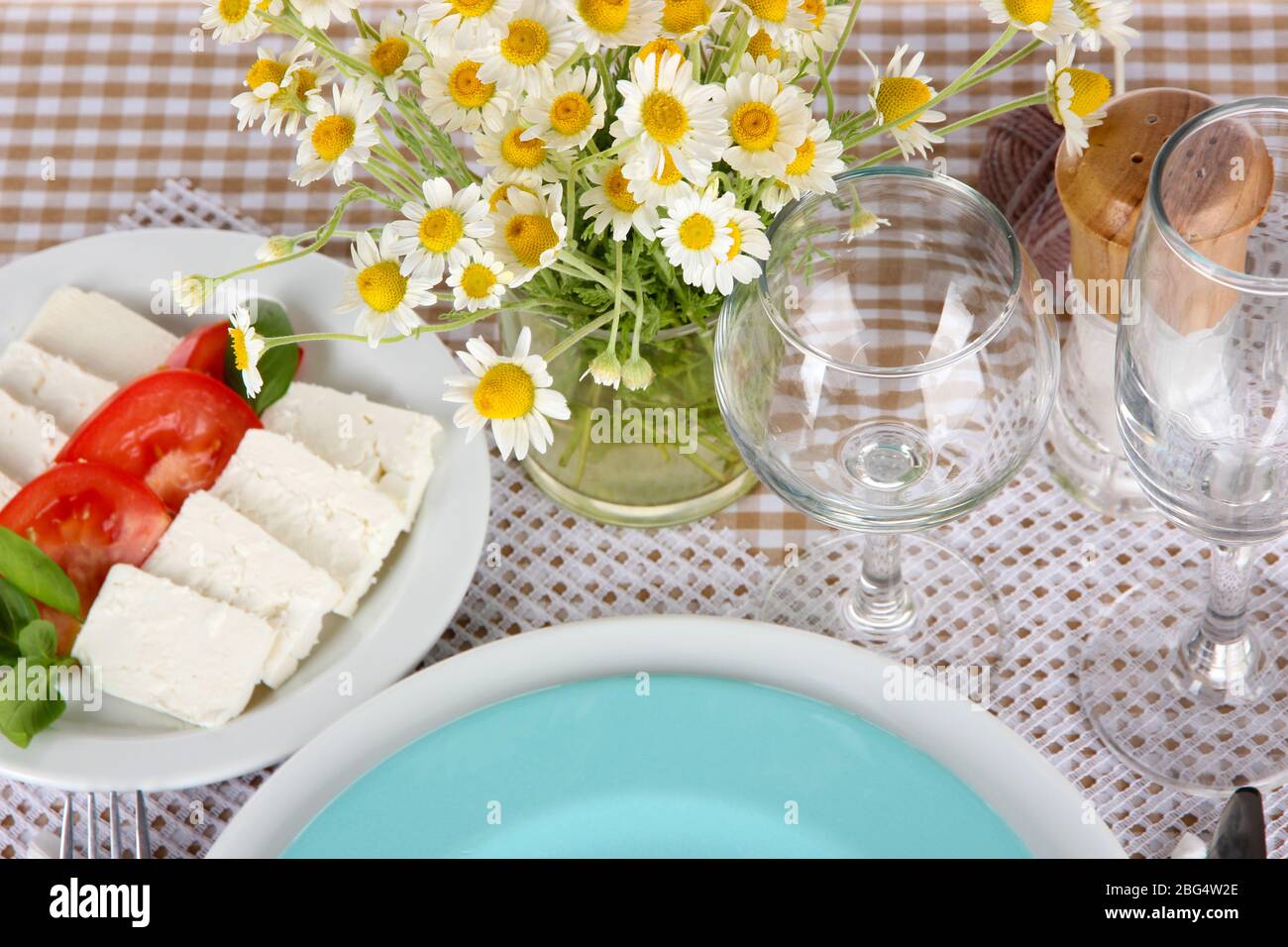 Table setting with chamomiles on checkered tablecloth Stock Photo