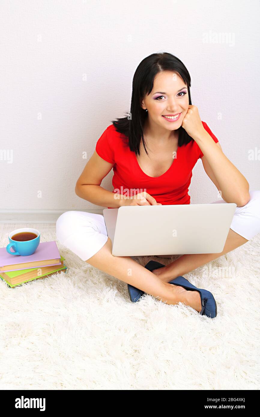 Beautiful young woman sitting with notebook in room Stock Photo - Alamy