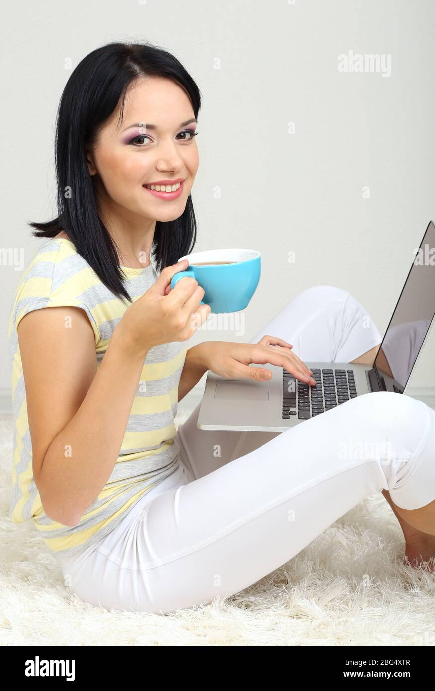 Beautiful young woman sitting with notebook in room Stock Photo - Alamy