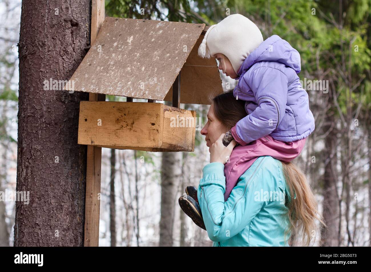 mother shows her daughter the bird feeder in the park Stock Photo
