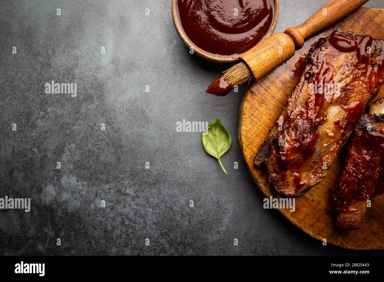 Delicious BBQ baby back ribs with tangy sauce and a basting brush