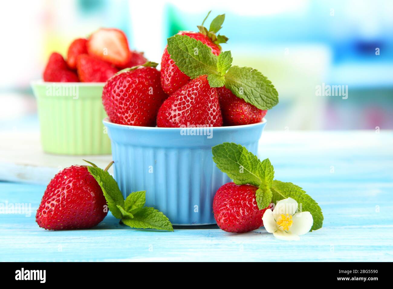 Ripe sweet strawberries in bowls on blue wooden table Stock Photo - Alamy