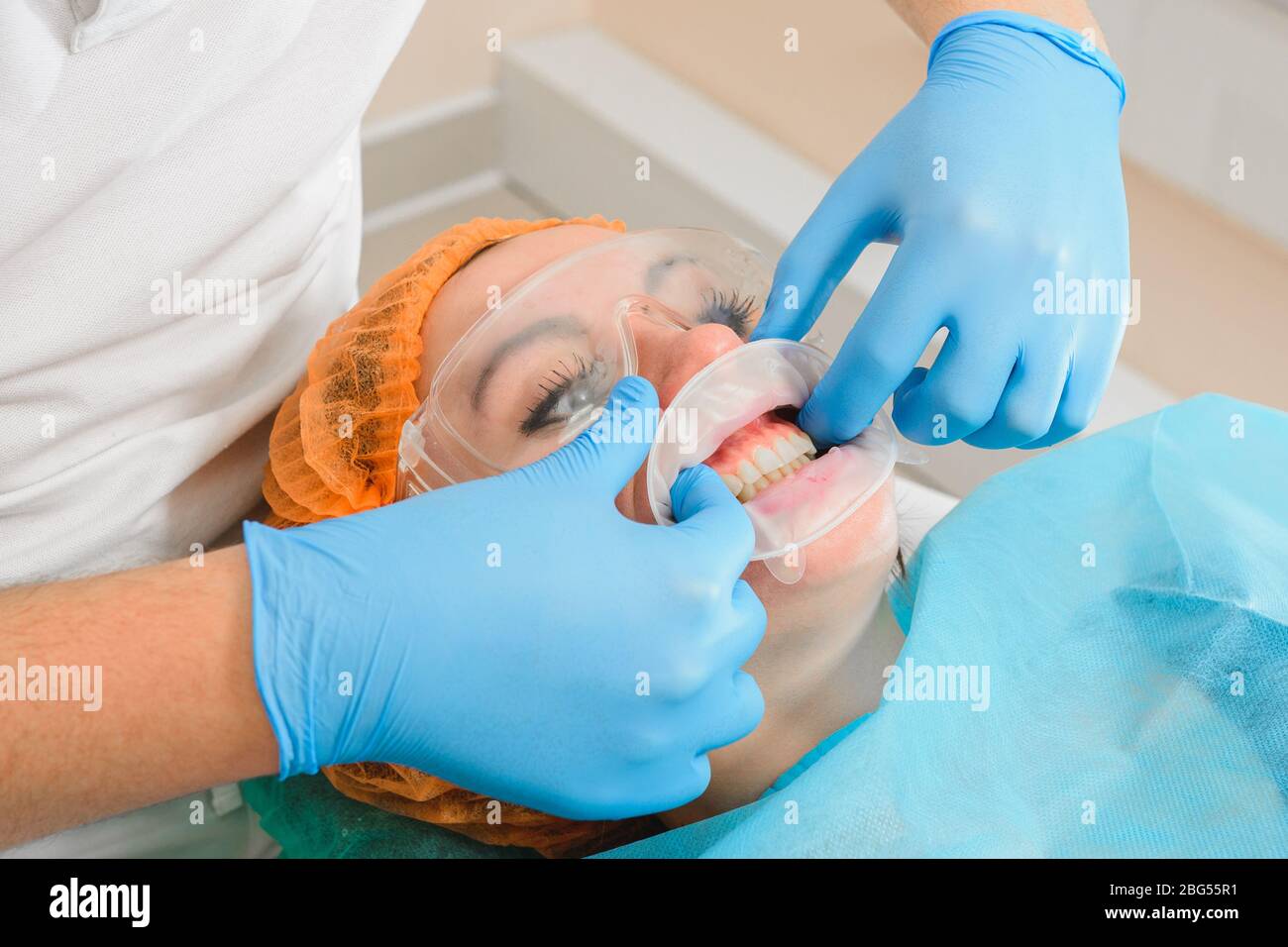 A young female dentist pulls a mouth extender at a dental clinic. 2020