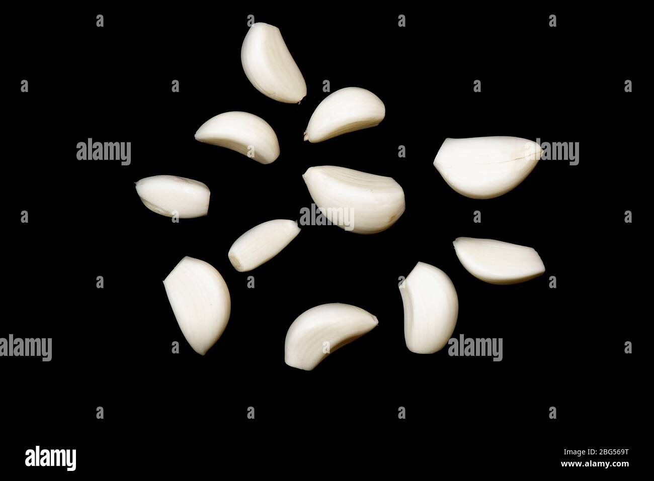 Some cloves of raw peeled garlic isolated on black background Stock Photo