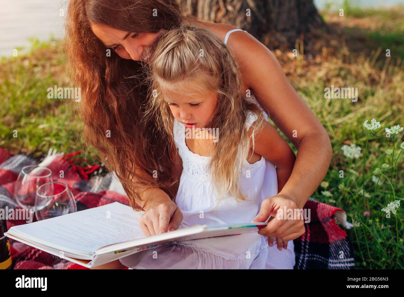 Mother's day, Women's day. Woman and her kids with grandmother reading books. Family having picnic in park Stock Photo