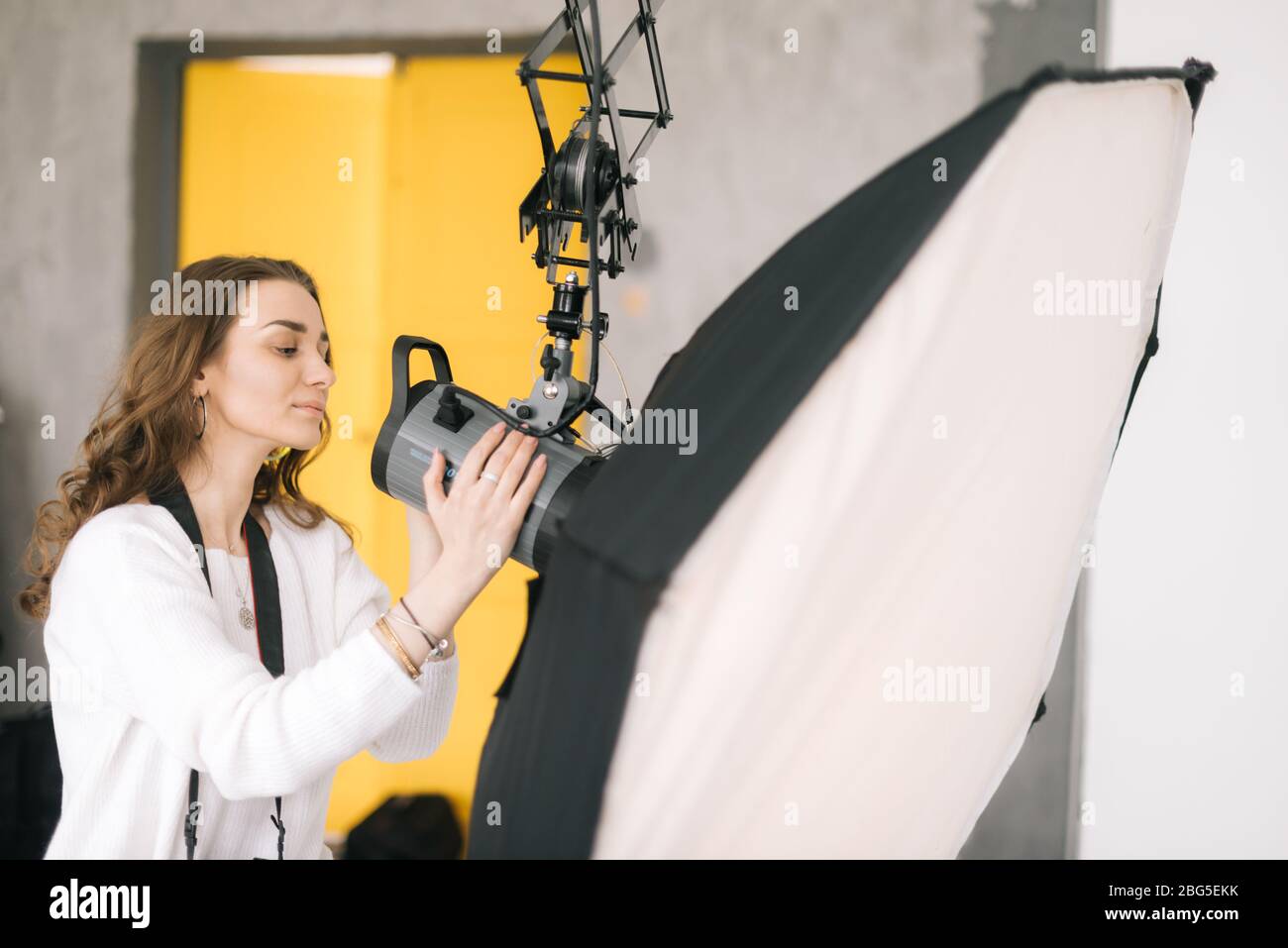 Woman photographer prepares light equipment softbox for photo shoot in the studio. Stock Photo