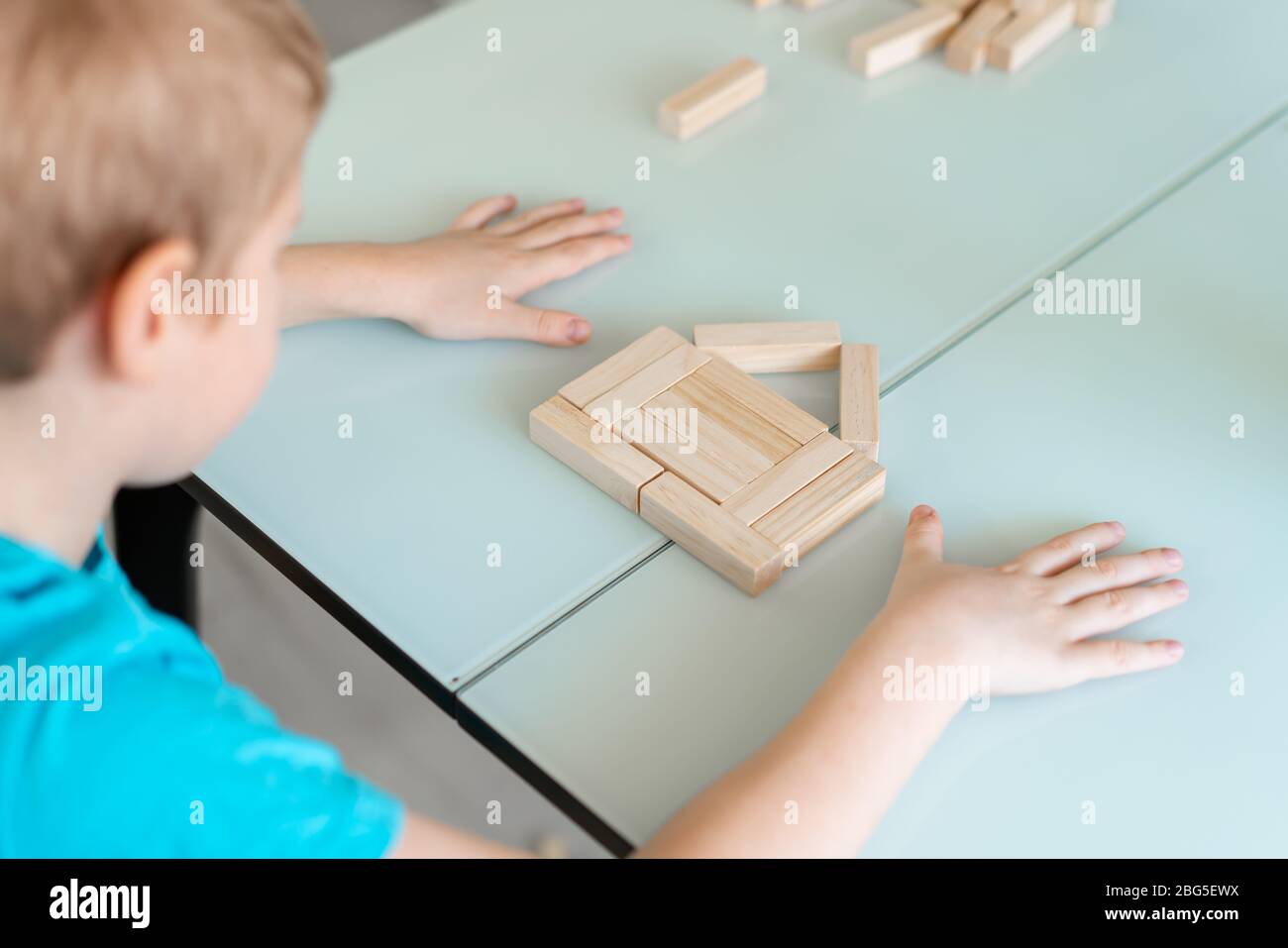 Close-up hands of little boy, assemble a house by wooden bricks. Concept stay home game Stock Photo