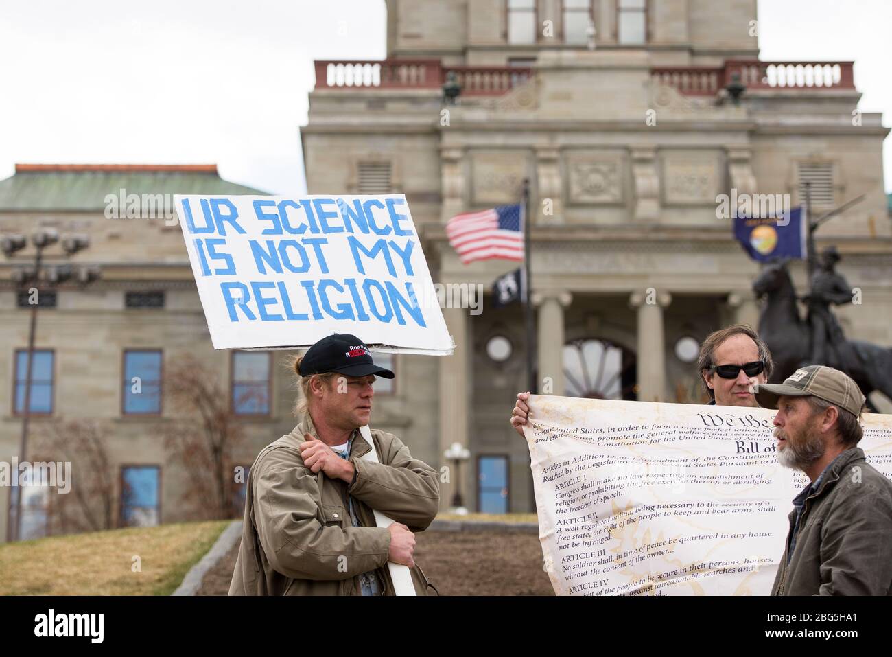 Helena, Montana - April 19, 2020: A man protesting wearing a hat carrying a science is not my religion sign at a Coronavirus shutdown rally at the Cap Stock Photo