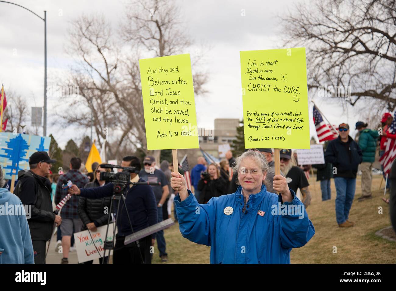 Helena, Montana - April 19, 2020: Senior citizen female protestor holding Bible scripture signs at a prayer rally at the state Capitol. Protesting the Stock Photo