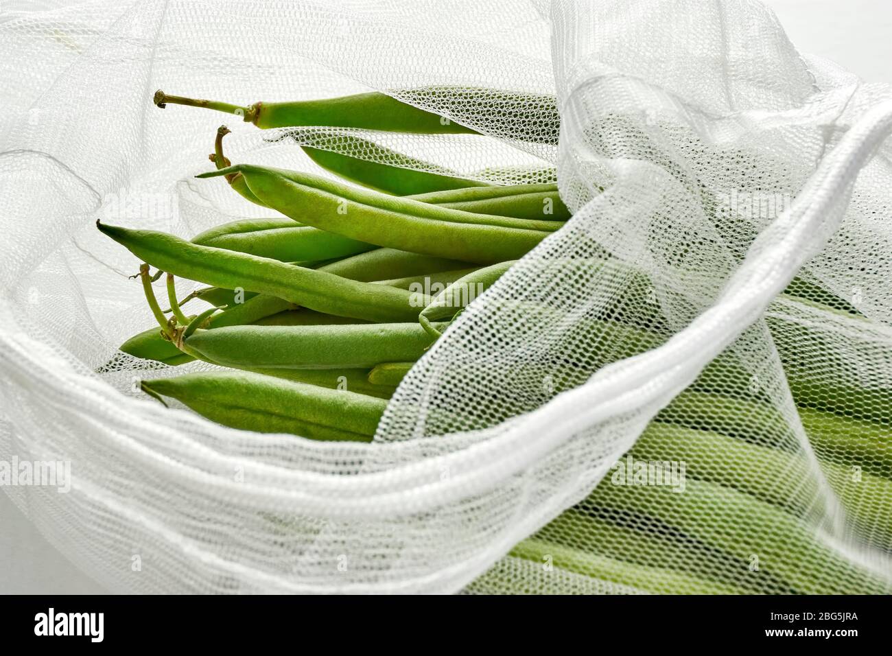Green beans in sustainable grocery mesh bag. Vegetables in reusable eco ...