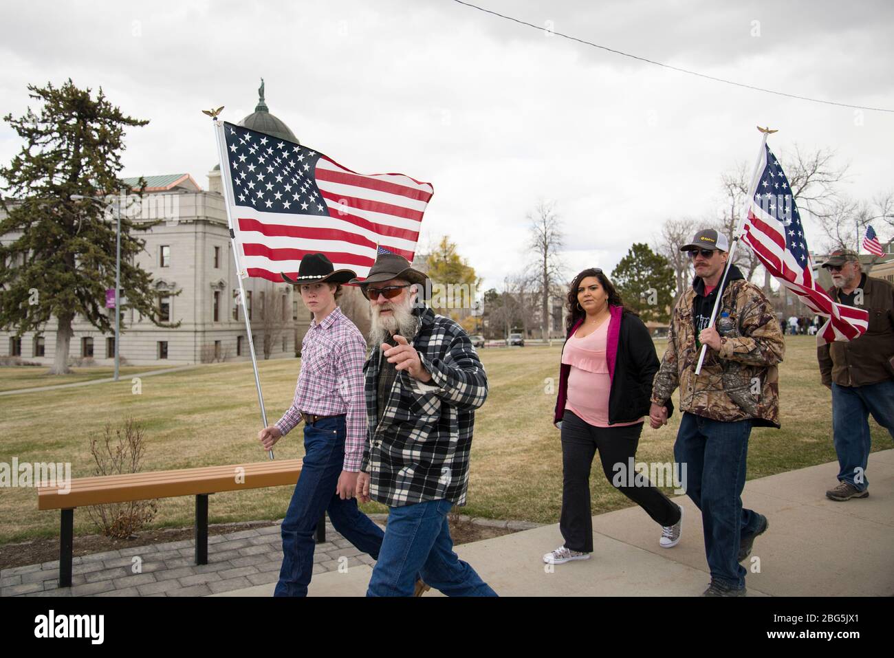 Helena, Montana - April 19, 2020: Group of protestors holding American flags, man looking at pointing at camera. Demonstrators at a protest against go Stock Photo