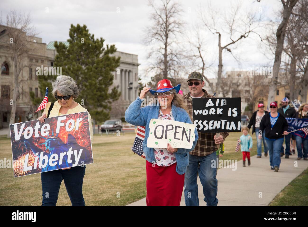 Helena, Montana - April 19, 2020: A woman wear an red white blue American flag costume at a protest to open the government shutdown. A man and women h Stock Photo