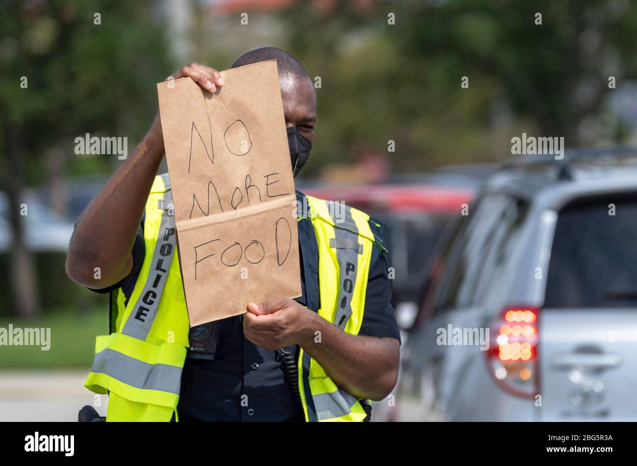 West Palm Beach, Florida, USA. 20th Apr, 2020. Police officer J. BUTLER holds a sign alerting people that there is no more at a drive-up food distribution center in the parking lot of the Palm Beach Outlets. People receive a one-week supply of a protein, fresh produce, eggs, milk, and other essential goods. The donations are limited to 800 cars on a first come first serve basis every Monday. Palm Beach Outlets partnered with Feeding South Florida to help those struggling during the coronavirus pandemic. Credit: Gregg Lovett/ZUMA Wire/Alamy Live News Stock Photo