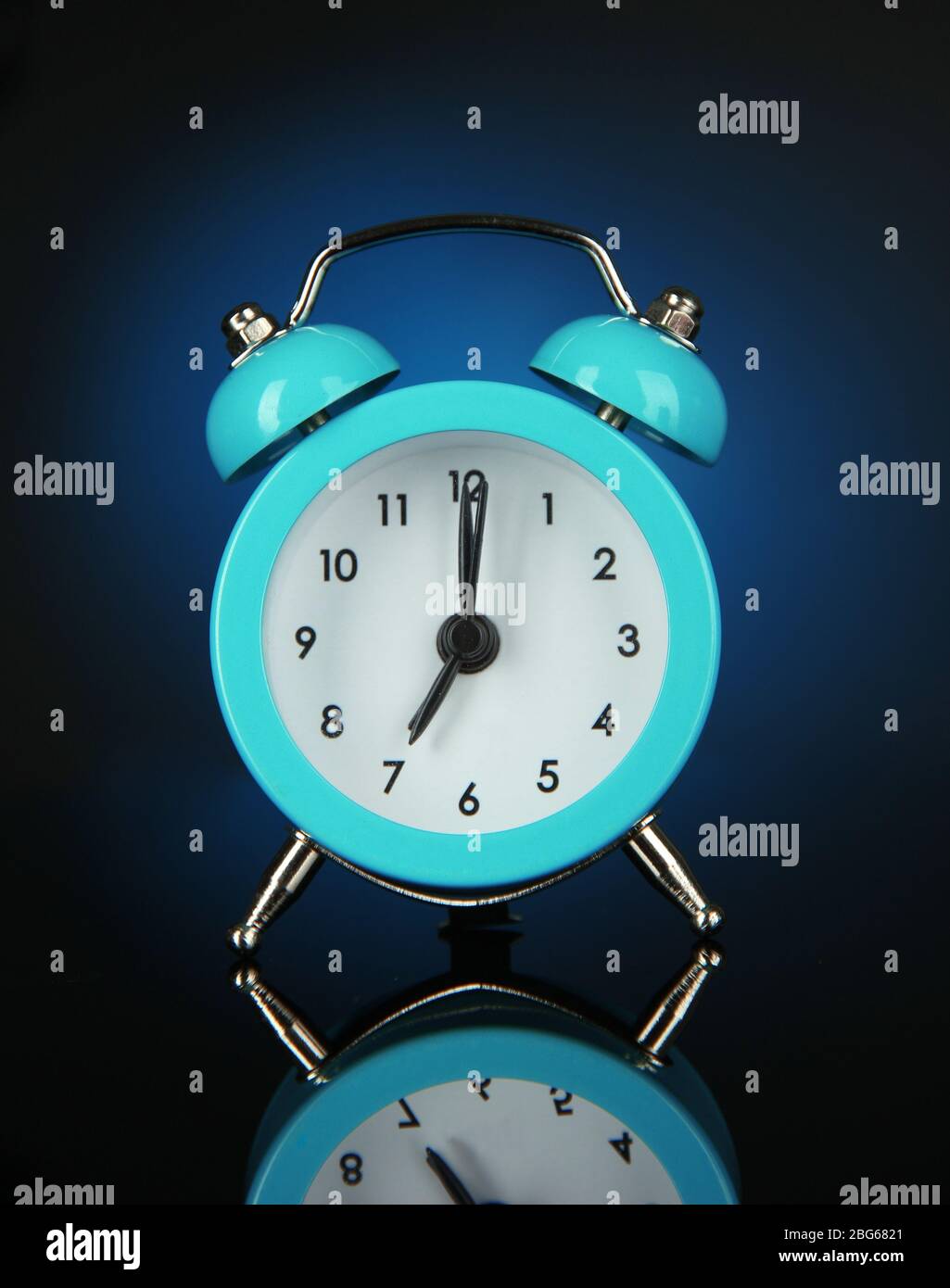 Blue alarm clock on dark blue background Stock Photo - Alamy
