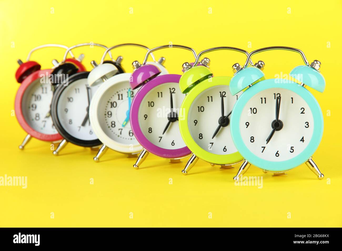 Colorful alarm clock on yellow background Stock Photo - Alamy