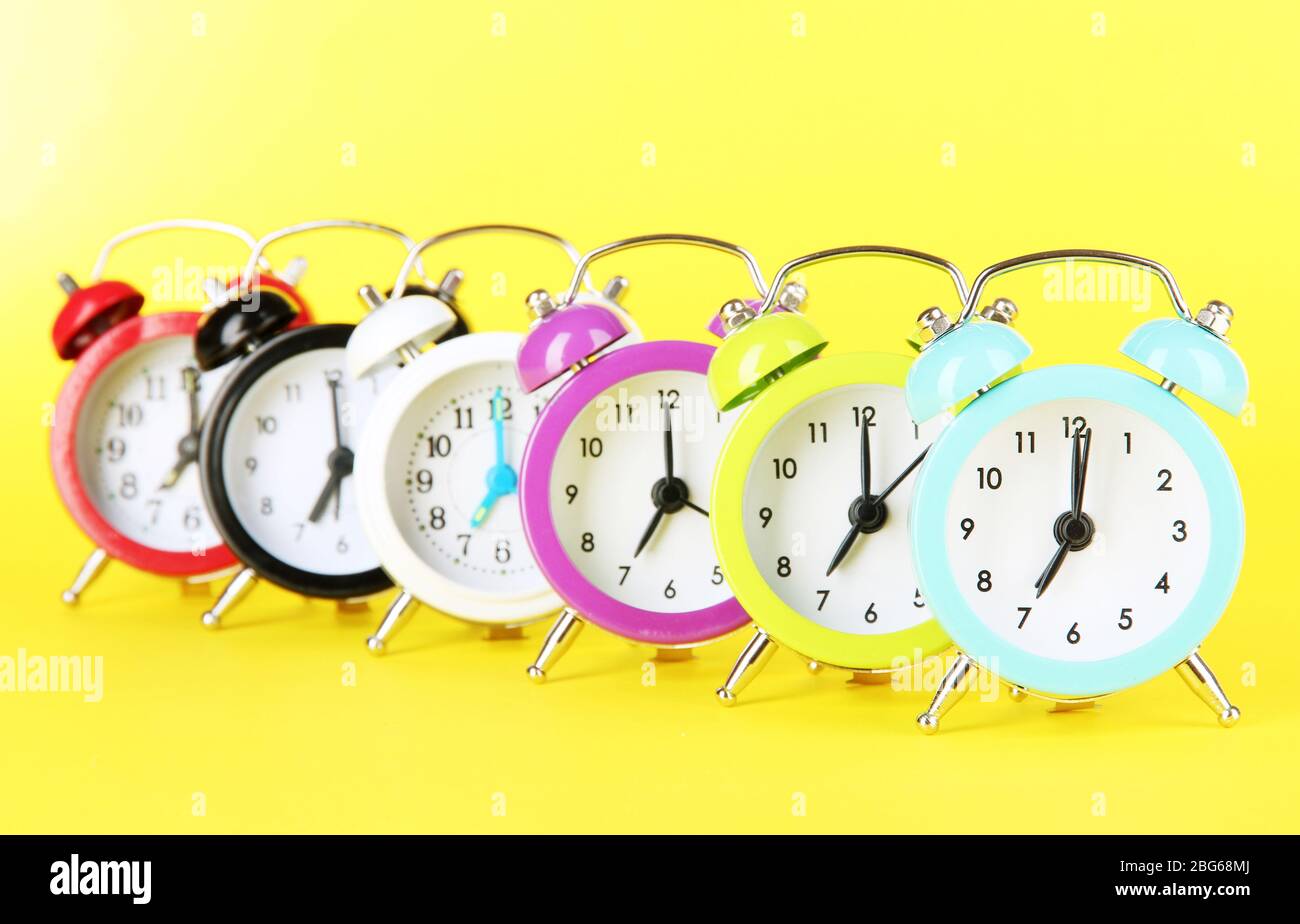 Colorful alarm clock on yellow background Stock Photo - Alamy