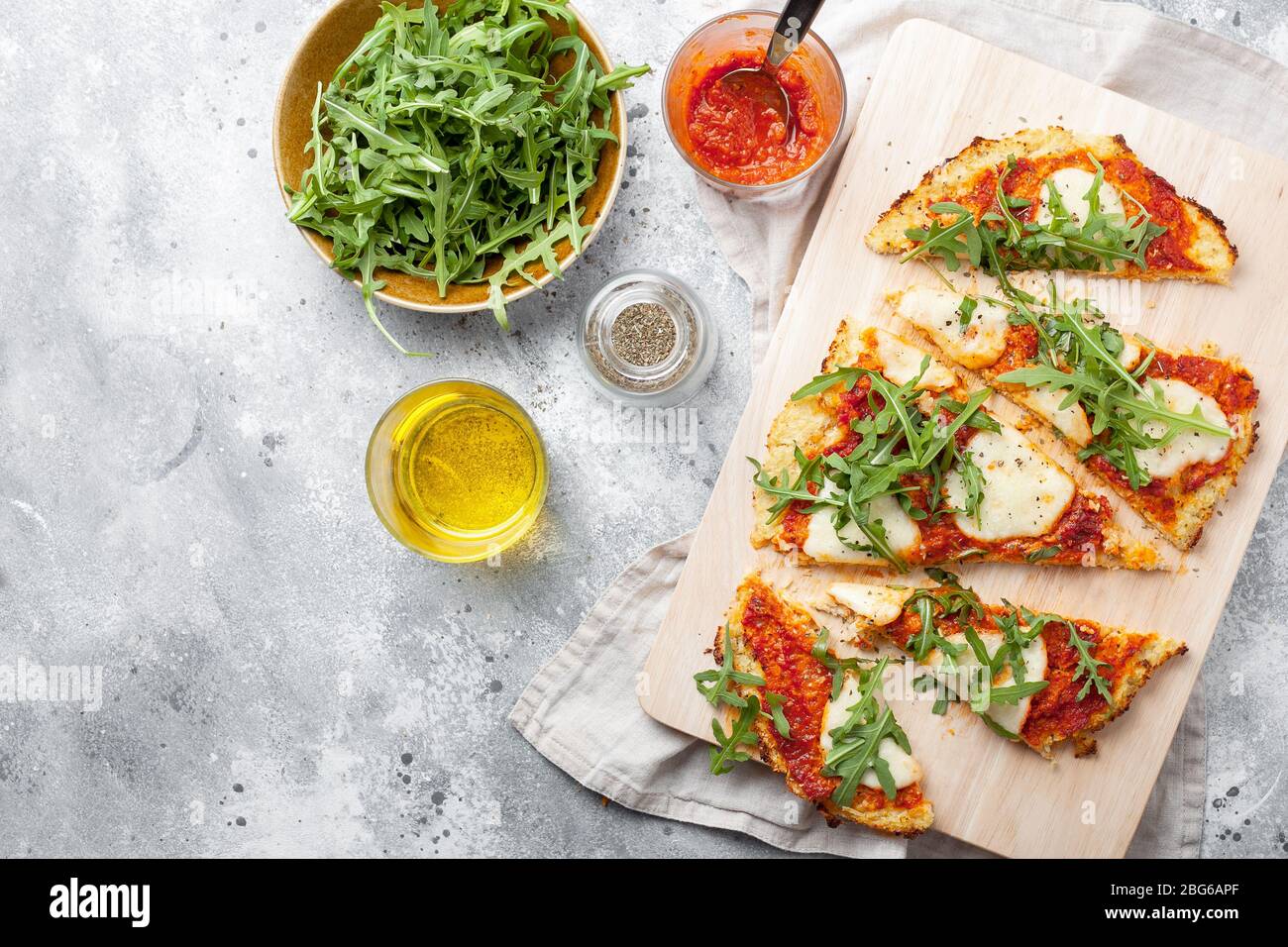 Homemade gluten-free Cauliflower pizza crust dough with tomatoes marinara sauce,mozzarella cheese on gray background.Vegetable alternative for low-car Stock Photo