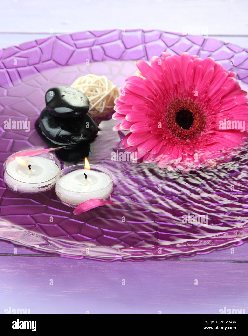 Spa stones, beautiful gerbera and candles on water Stock Photo - Alamy