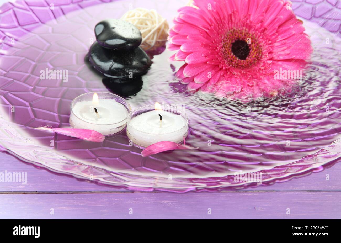 Spa stones, beautiful gerbera and candles on water Stock Photo - Alamy