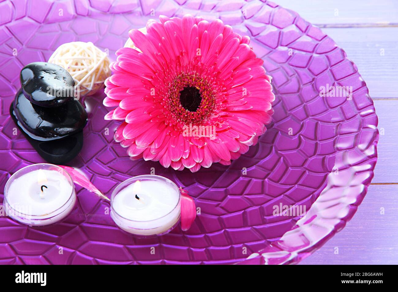Spa stones, beautiful gerbera and candles on water Stock Photo - Alamy