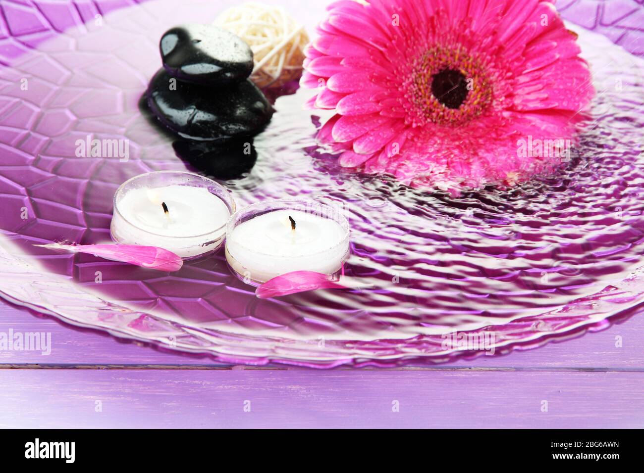 Spa stones, beautiful gerbera and candles on water Stock Photo - Alamy