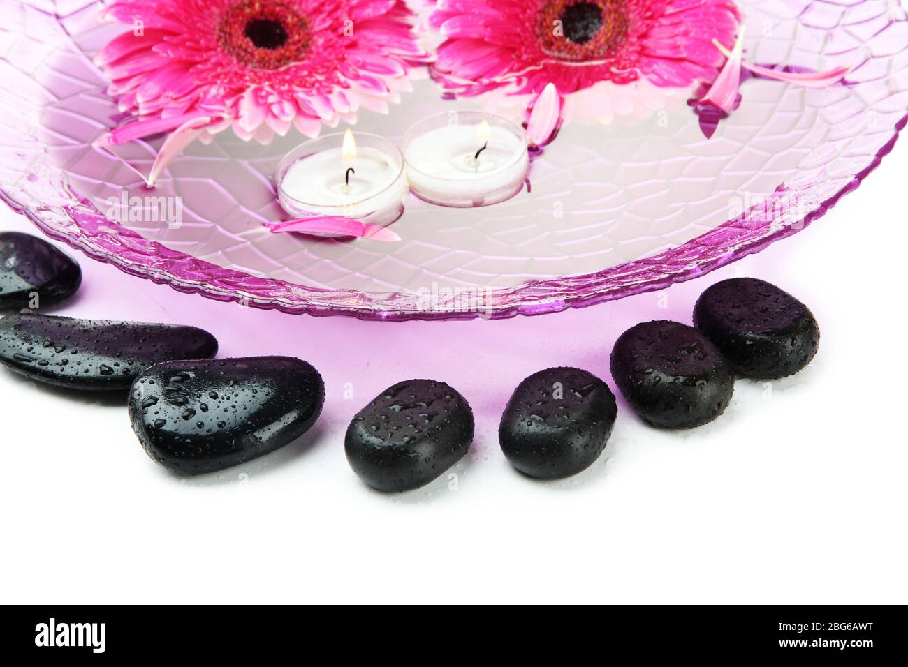 Spa stones, gerbera flowers and candles on water, isolated on white ...