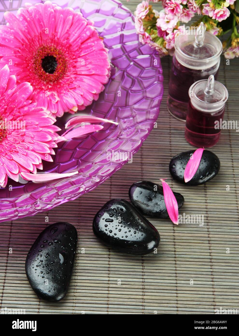 Gerbera flowers on water and spa stones on bamboo mat Stock Photo - Alamy