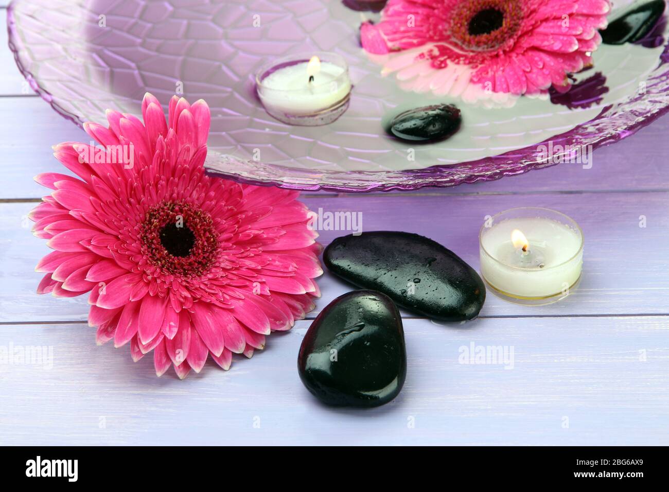 Spa stones, beautiful gerbera flowers and candles on water Stock Photo ...