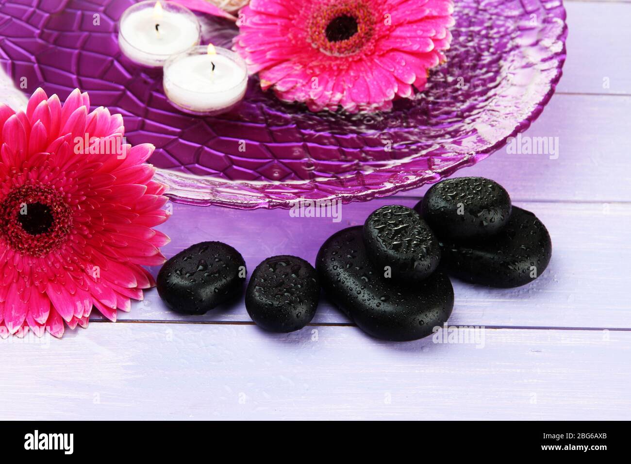 Spa stones, beautiful gerbera flowers and candles on water Stock Photo ...