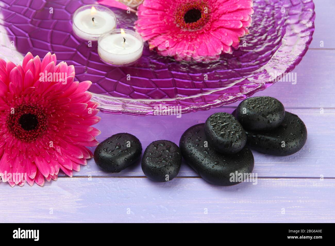 Spa stones, beautiful gerbera flowers and candles on water Stock Photo ...