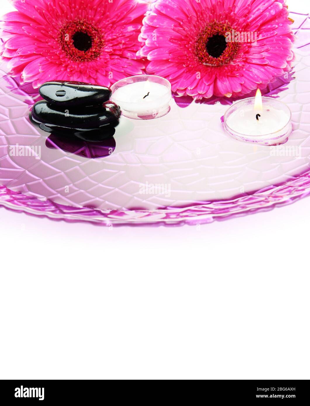 Spa stones, gerbera flowers and candles on water, isolated on white ...