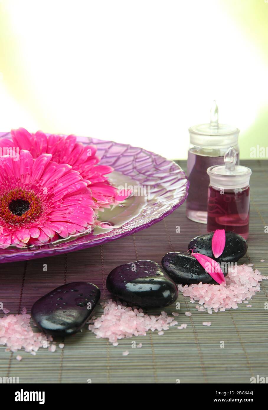 Gerbera flowers on water and spa stones on bamboo mat, isolated on ...