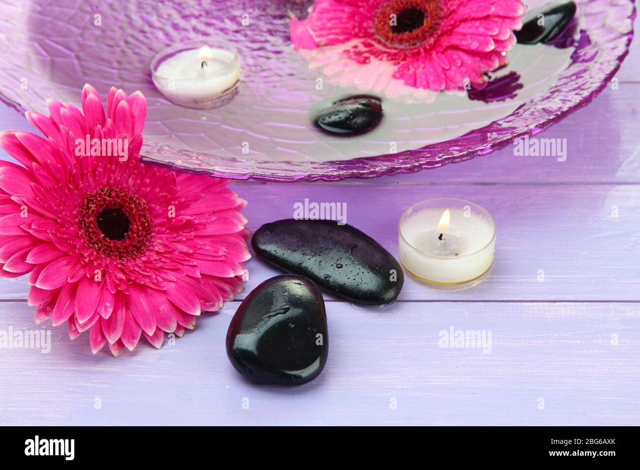 Spa stones, beautiful gerbera flowers and candles on water Stock Photo ...