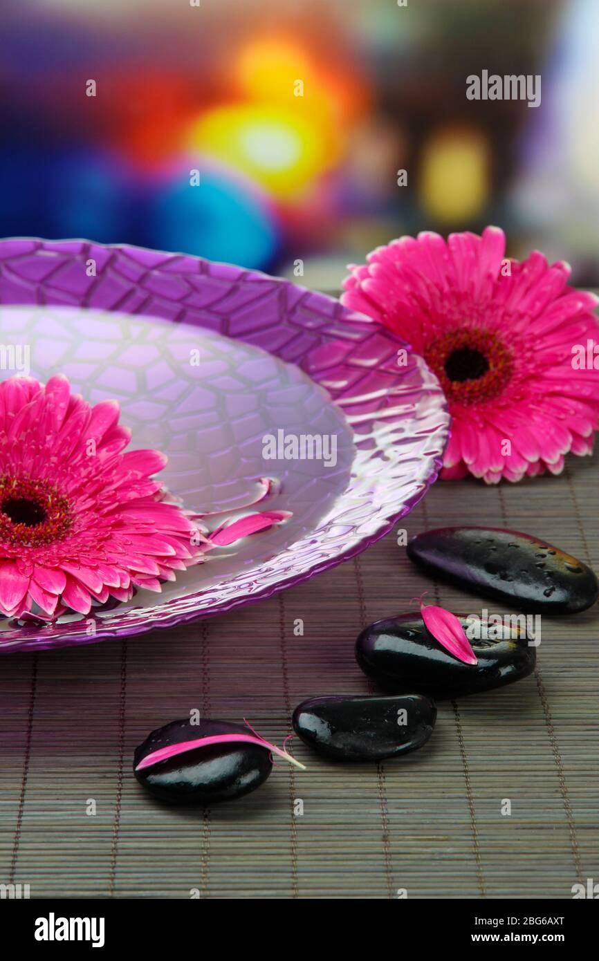 Gerbera flowers on water and spa stones on bamboo mat Stock Photo - Alamy