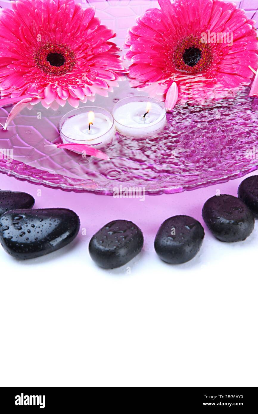 Spa stones, gerbera flowers and candles on water, isolated on white ...