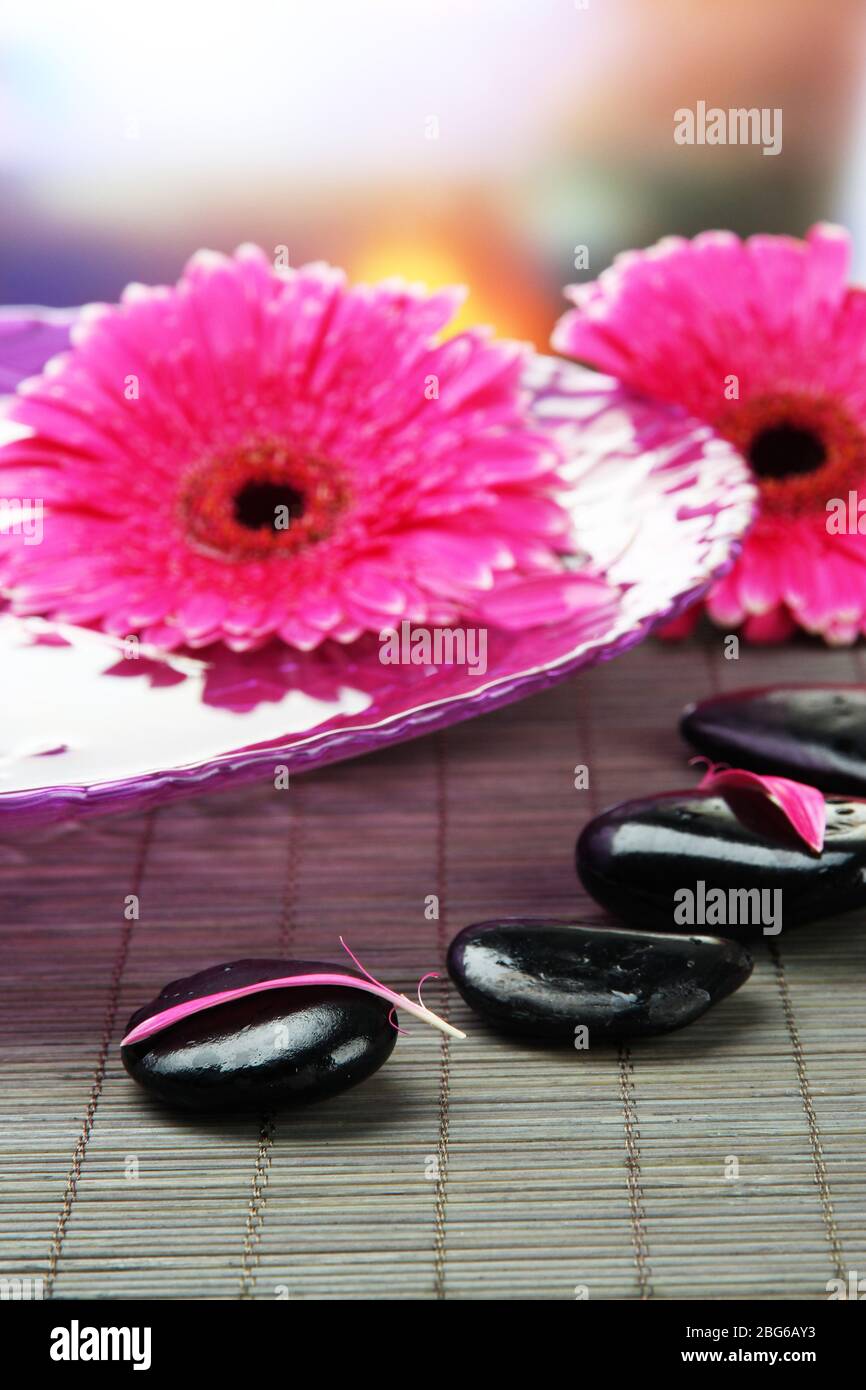 Gerbera flowers on water and spa stones on bamboo mat Stock Photo - Alamy