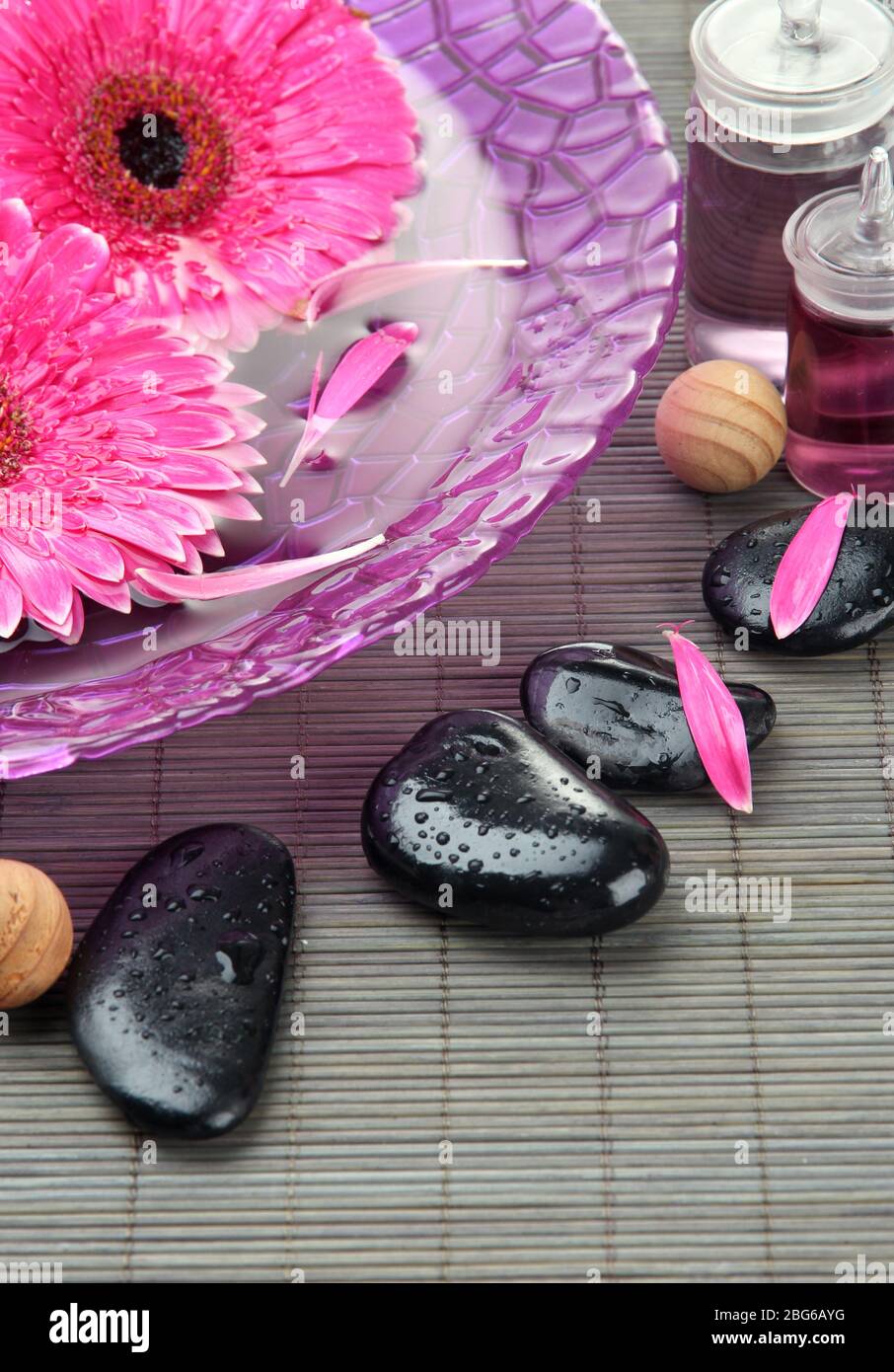 Gerbera flowers on water and spa stones on bamboo mat Stock Photo - Alamy