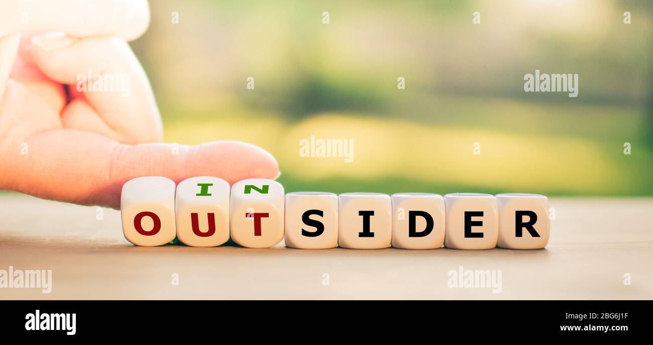 Hand turns dice and changes the expression 'outsider' to 'insider'. Stock Photo