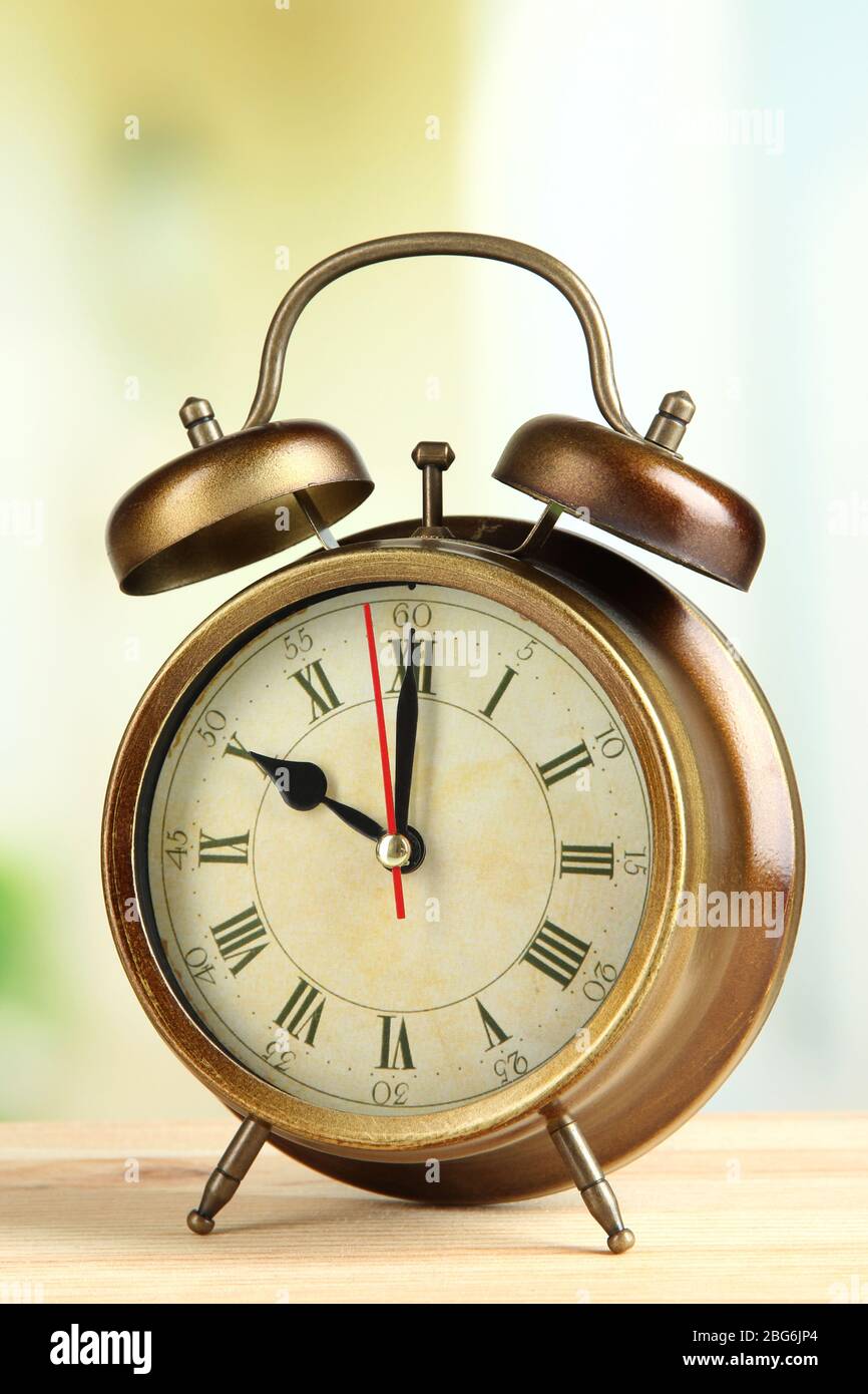 Old alarm clock on bright background Stock Photo - Alamy