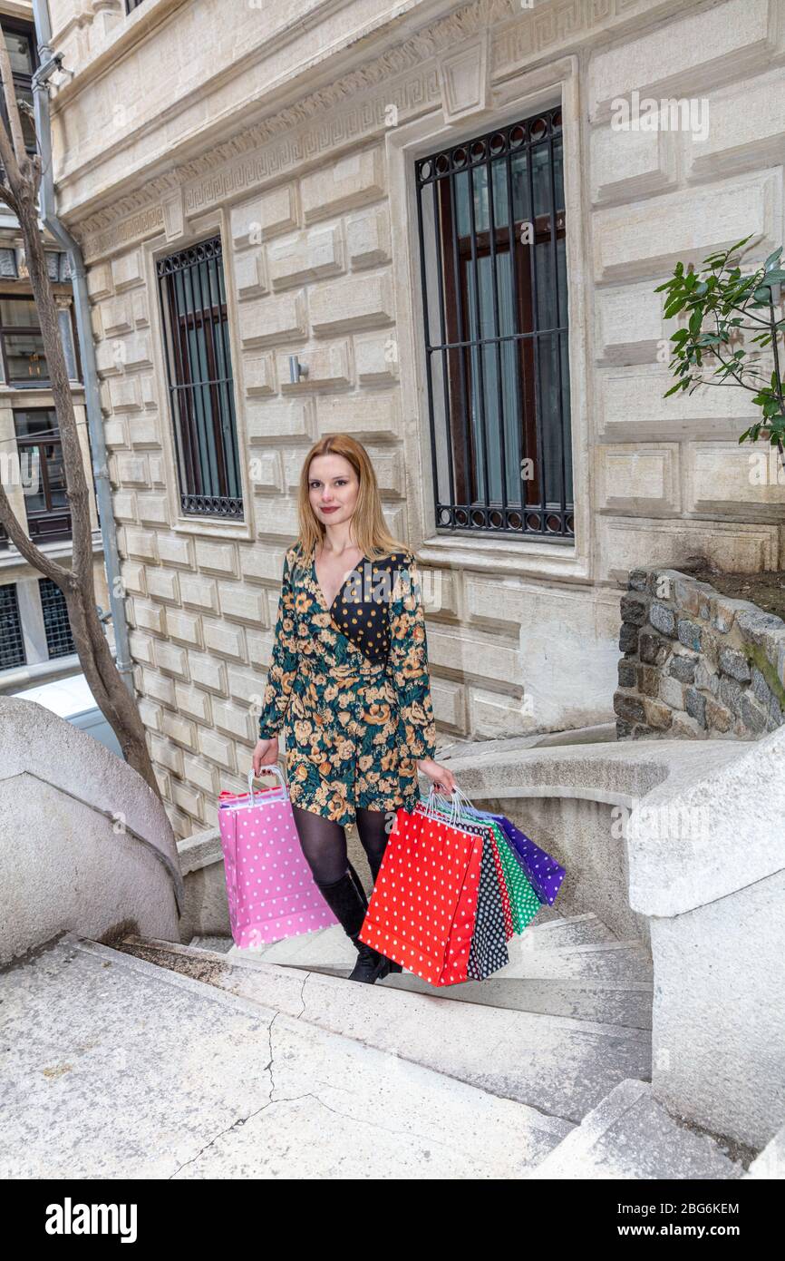 Attractive cute girl with the colorful shopping bags in her hands. Camondo Stairs (Turkish: Kamondo Merdivenleri) in Galata District in Istanbul, Turk Stock Photo