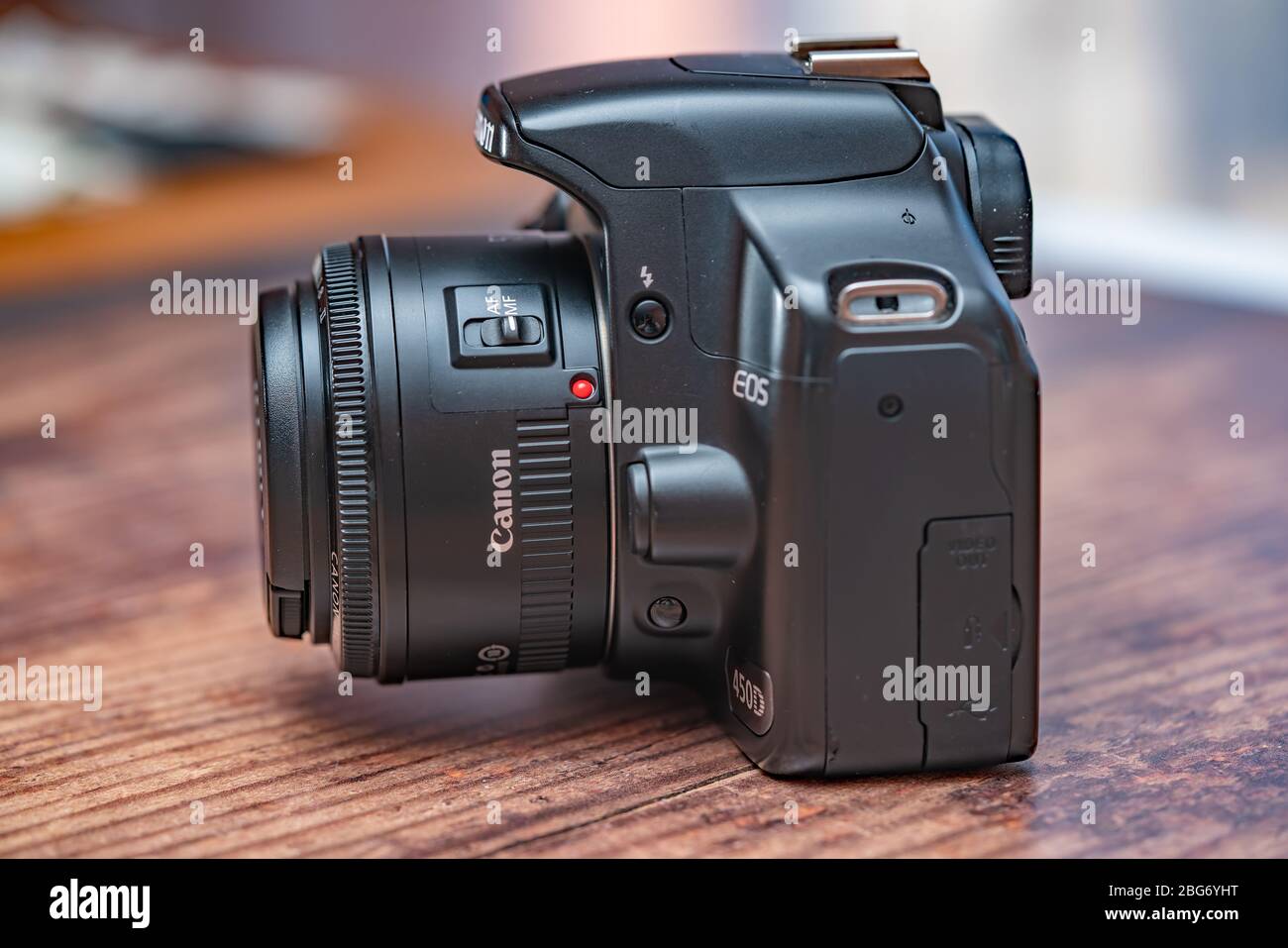 Norwich, Norfolk, UK – April 19 2020. Side on view of classic Canon EOS 450d dslr camera and 50mm f1.8 prime lens on a wooden table Stock Photo