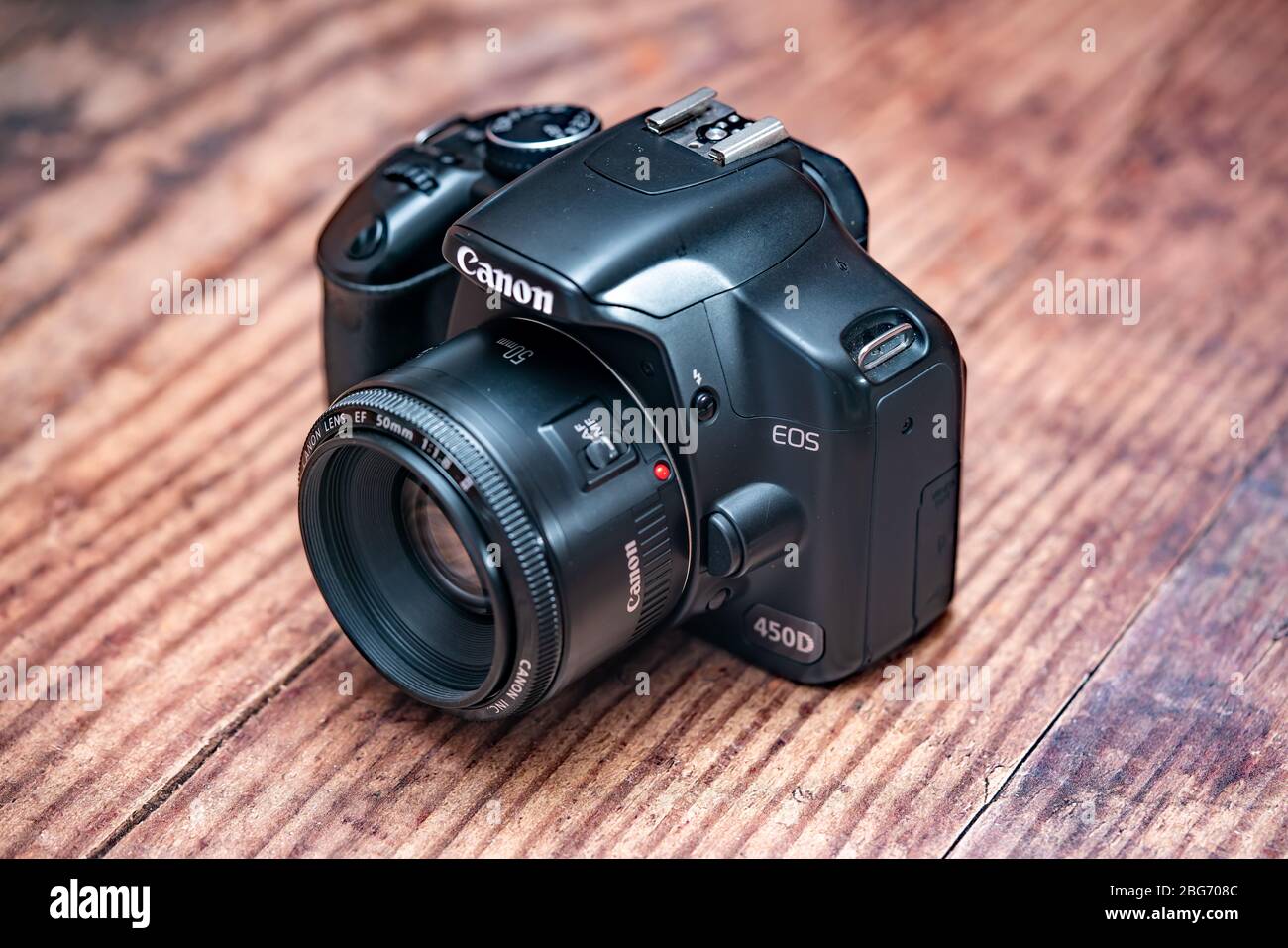 Norwich, Norfolk, UK – April 19 2020. Top down view of classic Canon EOS 450d dslr camera and 50mm f1.8 prime lens on a wooden table Stock Photo