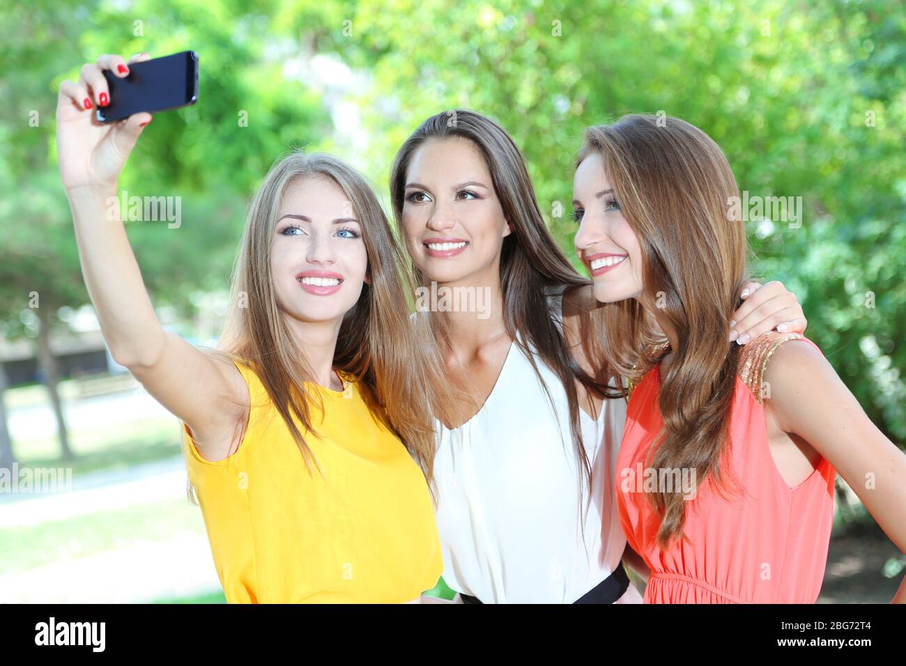 Three beautiful young woman taking picture in summer park Stock Photo ...