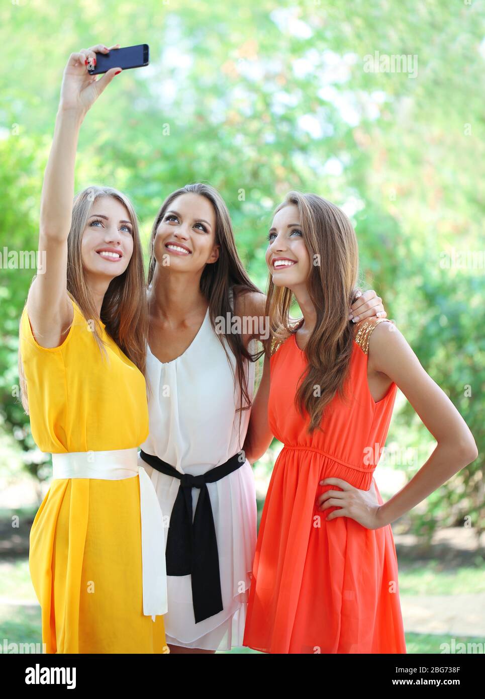 Three beautiful young woman taking picture in summer park Stock Photo ...