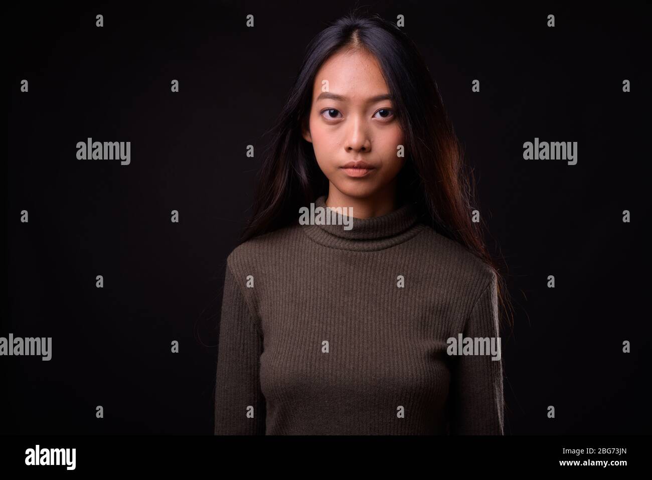 Young beautiful Asian woman against black background Stock Photo