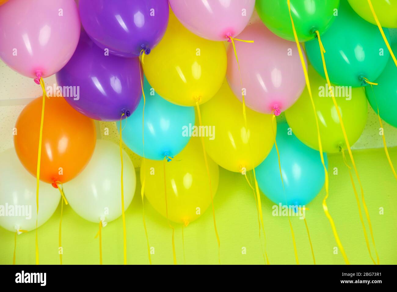 Colorful balloons on green wall background Stock Photo - Alamy