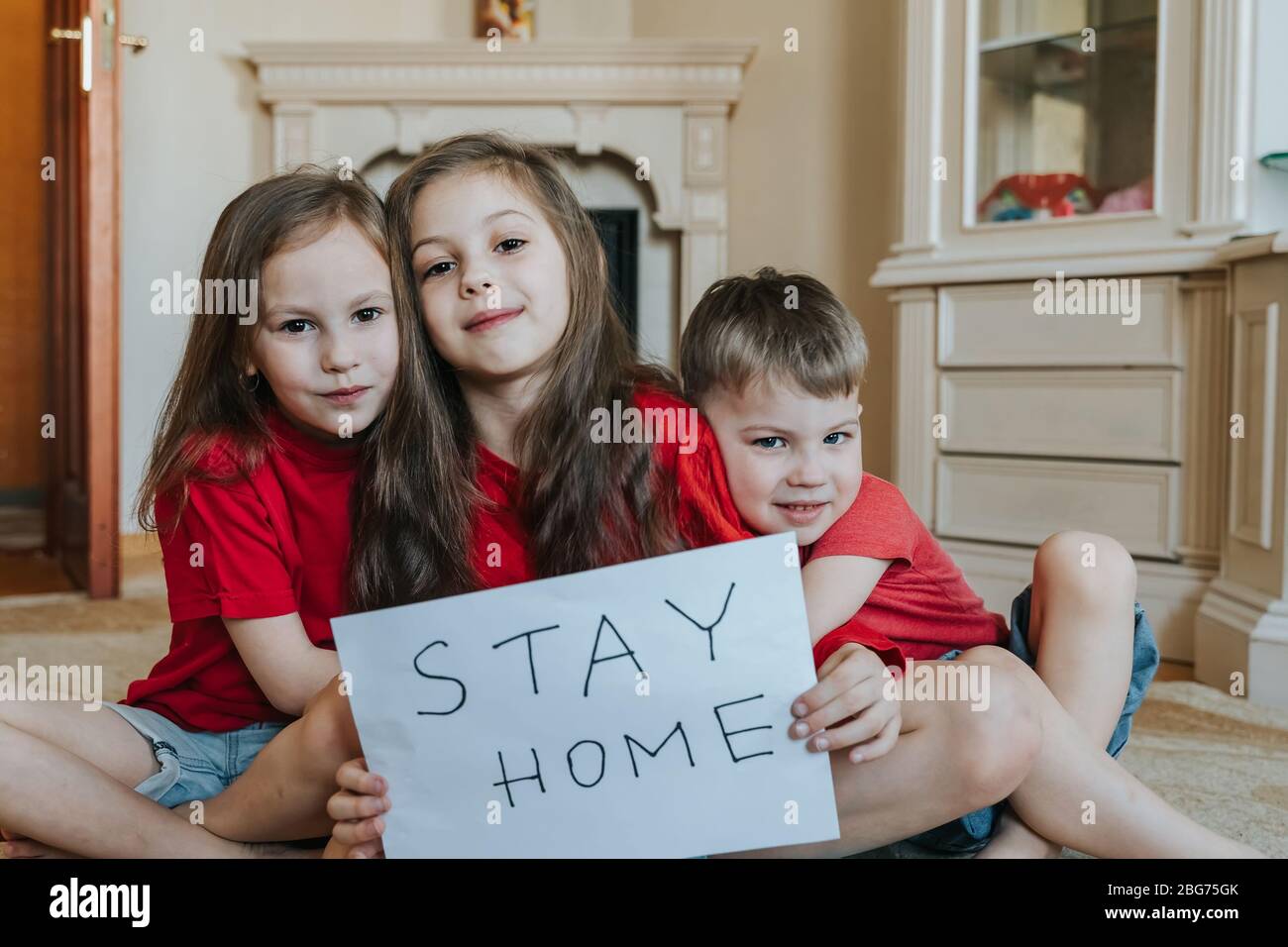 Family stay at home concept. Three children holding sign saying stay at home for virus protection and take care of their health from COVID-19 Stock Photo