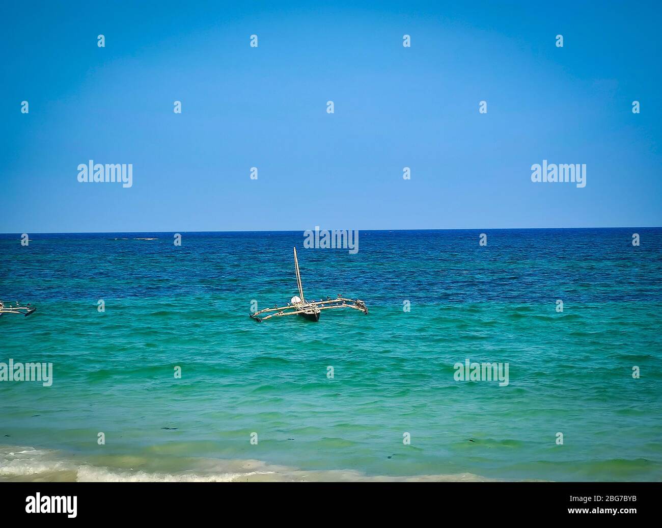 Typical Swahili wooden canoe on the sea at Diani beach, Kenya. It is a beautiful long beach in Africa. Stock Photo