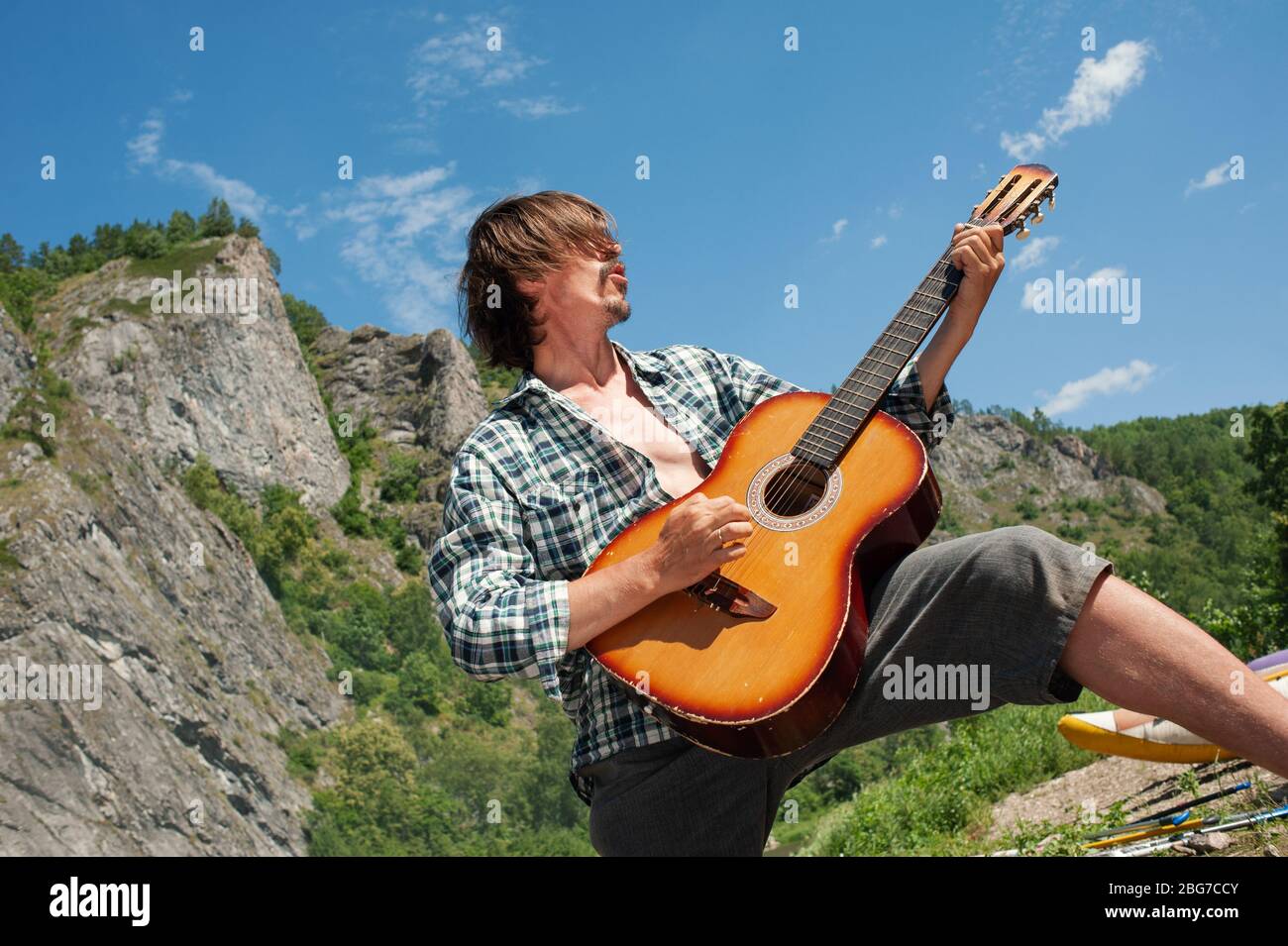 A male tourist plays a rock roll on a guitar overlooking the mountains. Enjoyment of outdoor recreation Stock Photo